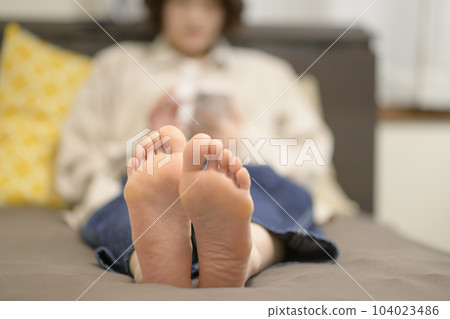 Young woman looking at smartphone in bed 104023486