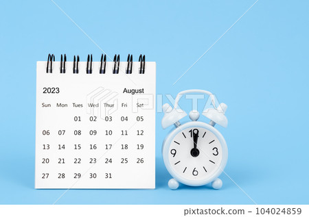 The August 2023 desk calendar and alarm clock on blue color background. 104024859