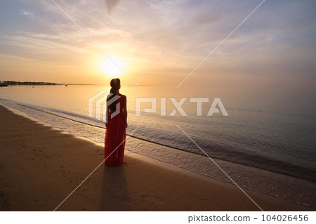 Young woman relaxing alone on ocean sand shore by seaside enjoying warm tropical evening. 104026456