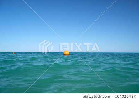 Yellow buoy floating on sea surface as marker for swimming restriction in deep water at tropical resort. Human life safety concept. 104026487
