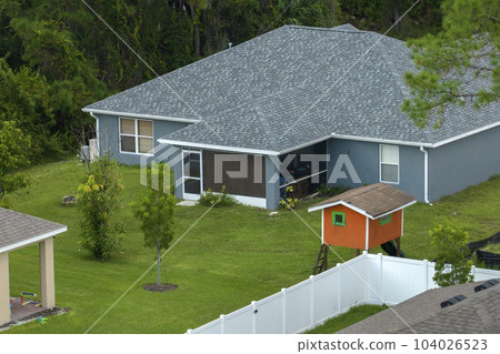 White vinyl picket fence on green lawn surrounding property grounds for backyard protection and privacy White vinyl picket fence on green lawn surrounding property grounds for backyard protection and privacy 104026523