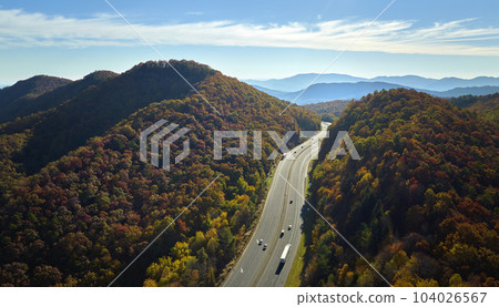 View from above of I-40 freeway route in North Carolina leading to Asheville thru Appalachian mountains with yellow fall woods and fast moving trucks and cars. Interstate transportation concept View from above of I-40 freeway route in North Carolina leading to Asheville thru Appalachian mountains with yellow fall woods and fast moving trucks and cars. Interstate transportation concept 104026567