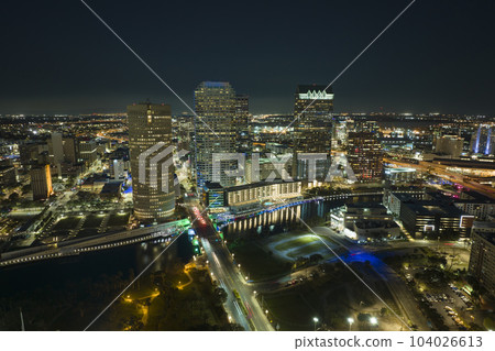 View from above of brightly illuminated high skyscraper buildings and moving traffic in downtown district of Tampa city in Florida, USA. American megapolis with business financial district at night View from above of brightly illuminated high skyscraper buildings and moving traffic in downtown district of Tampa city in Florida, USA. American megapolis with business financial district at night 104026613
