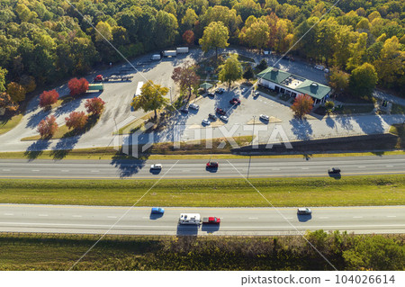 View from above of big parking rest area for cars and trucks near busy american highway with fast moving traffic. Recreational place during interstate travel 104026614