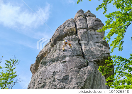 Strong male climber climbing steep wall of rocky mountain. Sportsman overcoming difficult route. Engaging in extreme sports hobby concept. Strong male climber climbing steep wall of rocky mountain. Sportsman overcoming difficult route. Engaging in extreme sports hobby concept. 104026848