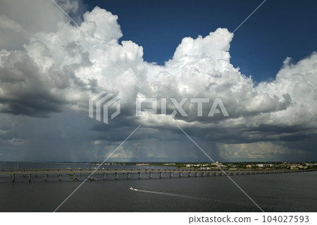 Heavy thunderstorm approaching traffic bridge connecting Punta Gorda and Port Charlotte over Peace River. Bad weather conditions for driving during rainy season in Florida 104027593