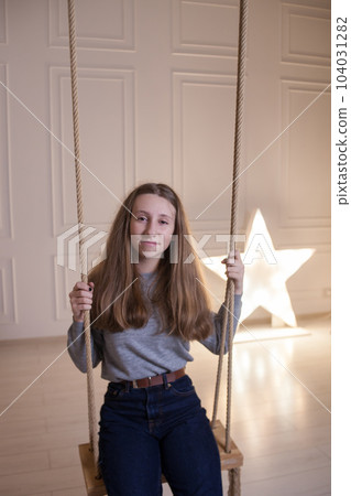 Cute happy girl with smile holding ropes on the swing chair Cute happy girl with smile holding ropes on the swing chair 104031282