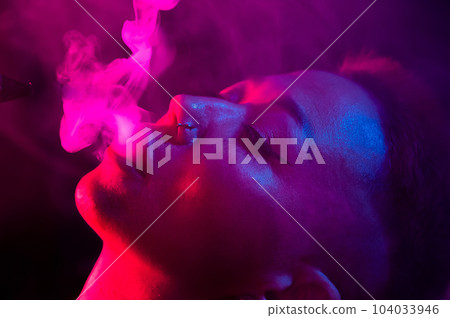 Close up portrait of asian woman with short hair smoking in neon light.  104033946