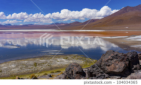 Scene of salt lagoon reflecting mountains and clouds as if in a mirror Scene of salt lagoon reflecting mountains and clouds as if in a mirror 104034365