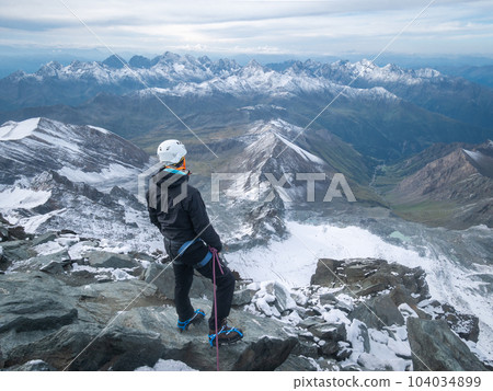Mountaineer enjoying views on alpine landscape after reaching peak summit, Austrian Alps, Europe 104034899