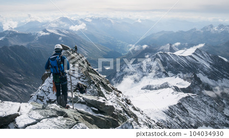 Mountaineers moving through narrow mountain ridge in beautiful alpine environment, Austria, Europe 104034930
