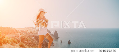 Woman summer travel sea. Happy tourist enjoy taking picture outdoors for memories. Woman traveler posing over sea bay surrounded by volcanic mountains, sharing travel adventure journey Woman summer travel sea. Happy tourist enjoy taking picture outdoors for memories. Woman traveler posing over sea bay surrounded by volcanic mountains, sharing travel adventure journey 104035810