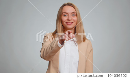 Woman pointing to camera and looking with playful happy expression, making choice, showing direction 104036302