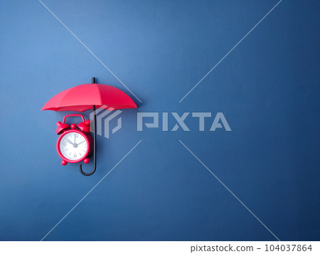 Red umbrella and red alarm clock on a blue background with copy space. Red umbrella and red alarm clock on a blue background with copy space. 104037864
