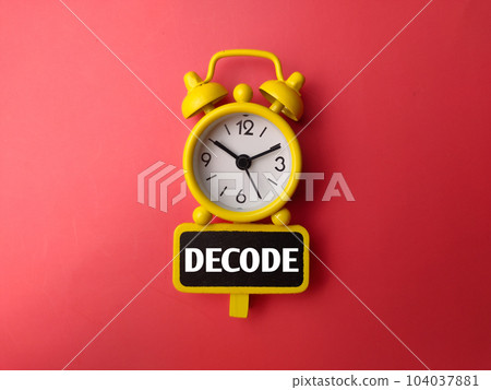 Yellow alarm clock and wooden board with word DECODE on a red background Yellow alarm clock and wooden board with word DECODE on a red background 104037881