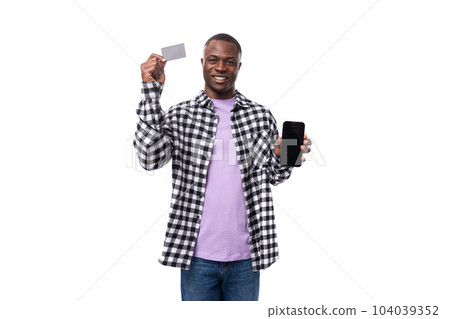 a handsome 30 year old African guy dressed in a plaid black and white shirt demonstrates a bank card 104039352