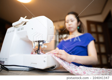 Woman using a sewing machine Woman using a sewing machine 104041347