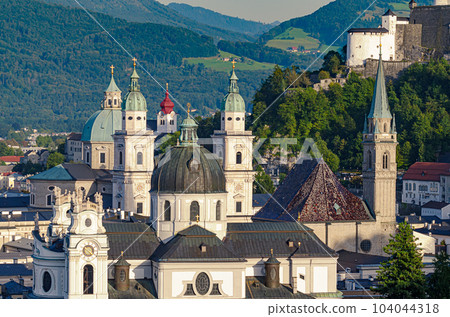 Salzburg, city in Austria, view at the old town and historic centre, with Collegiate Church, Franciscan Church and Salzburg Cathedral. In the distance a part of the medieval Hohensalzburg Fortress. Salzburg, city in Austria, view at the old town and historic centre, with Collegiate Church, Franciscan Church and Salzburg Cathedral. In the distance a part of the medieval Hohensalzburg Fortress. 104044318