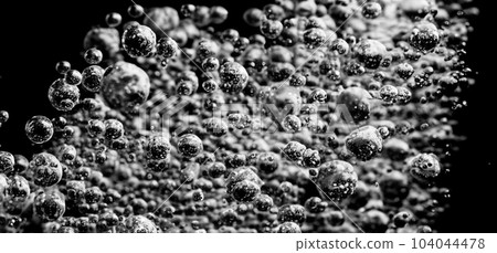 Soda water bubbles splashing underwater against black background. Cola liquid texture that fizzing and floating up to surface like a explosion in under water for refreshing carbonate drink concept. 104044478