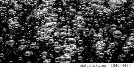Soda water bubbles splashing underwater against black background. Cola liquid texture that fizzing and floating up to surface like a explosion in under water for refreshing carbonate drink concept. Soda water bubbles splashing underwater against black background. Cola liquid texture that fizzing and floating up to surface like a explosion in under water for refreshing carbonate drink concept. 104044484