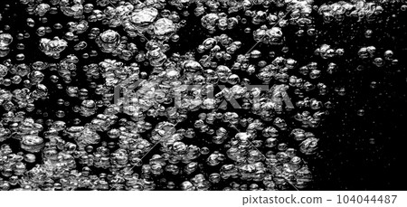 Soda water bubbles splashing underwater against black background. Cola liquid texture that fizzing and floating up to surface like a explosion in under water for refreshing carbonate drink concept. 104044487