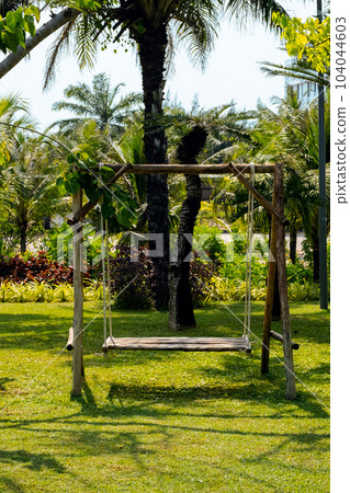 Hanging swing on backyard against palm trees. Summertime mood. Hanging swing on backyard against palm trees. Summertime mood. 104044603