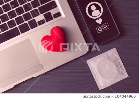 Red heart on laptop with phone and condom for online dating love chat match flirty concept. 104044960