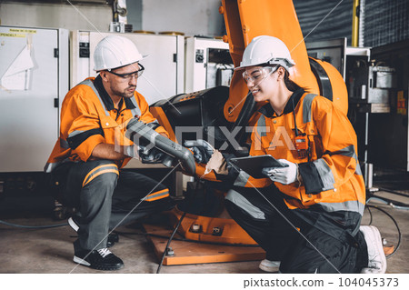 engineer team working together training new staff worker to operate hand control robot arm welding machine in automation factory heavy industry. 104045373