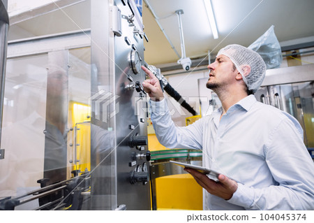 Engineer male working setup automatic machine in food beverage industry factory. Engineer male working setup automatic machine in food beverage industry factory. 104045374