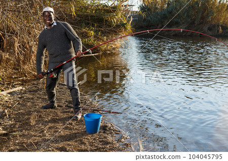 Man and pulling fish near river Man and pulling fish near river 104045795