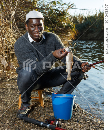 Fisherman holding fish in his hands 104045807