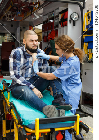 Paramedic team providing first aid to man 104045839