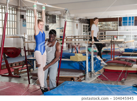 Athletic African male coach helping teenage girl Athletic African male coach helping teenage girl 104045945