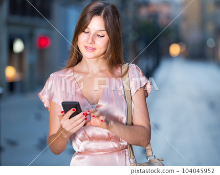 woman looking to phone in hands and chatting in city woman looking to phone in hands and chatting in city 104045952