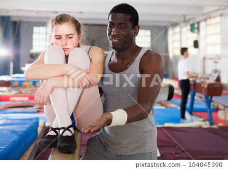 Adult male coach comforting sad teenage girl Adult male coach comforting sad teenage girl 104045990