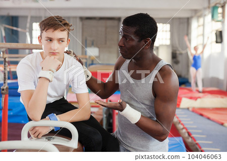 African coach soothing unhappy teenage athlete 104046063