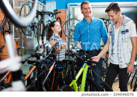 Seller helping customers to buying new bicycle in sport store 104046076