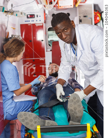 Paramedic team moving man on stretcher 104046363