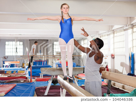 Trainer helping girl at gym Trainer helping girl at gym 104046386