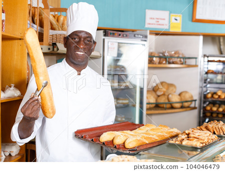 Baker working behind counter in bakeshop 104046479