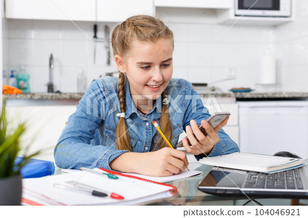 Girl doing home task using mobile phone 104046921
