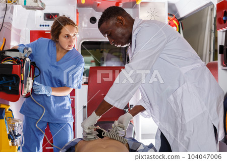 thoughtful afro paramedical using defibrillator for providing medical care to patient 104047006
