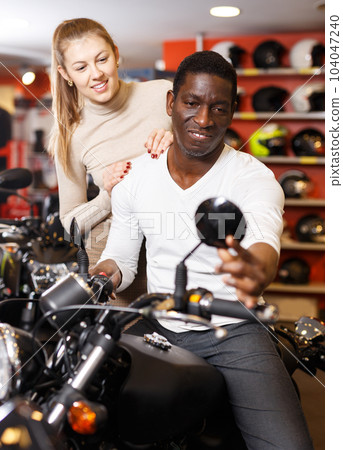 couple in motorcycle shop choosing new vehicle couple in motorcycle shop choosing new vehicle 104047240