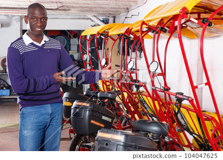Confident cheerful African-American man recommending traveling with rickshaw Confident cheerful African-American man recommending traveling with rickshaw 104047625