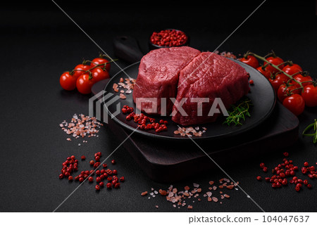 Raw beef eye steak round with salt, spices and herbs 104047637