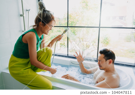 Funny playful asian couple lover play in the bathtub in the bathroom. Funny playful asian couple lover play in the bathtub in the bathroom. 104047811