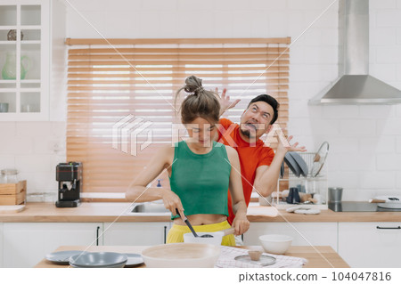 Husband feels worry behind his wife while she is cooking for him. 104047816