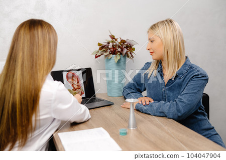 Young pregnant woman visiting her gynecologist in modern clinic. Woman sitting on chair and talking to her doctor 104047904