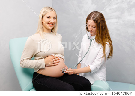 Female doctor using stethoscope examining pregnant woman in clinic. Medical exam pregnant woman 104047907