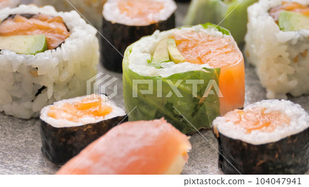 Sushi rolls with avocado maki taken wooden chopsticks. Vegetarian food 104047941